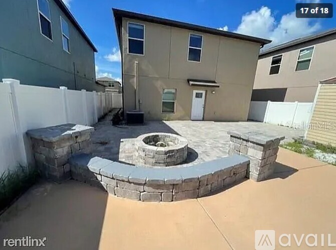 A backyard with a fire pit and a white fence.