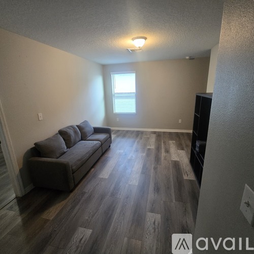 A living room with a grey couch and wooden flooring.