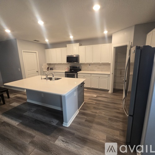 A kitchen with white cabinets and a large island in the middle.