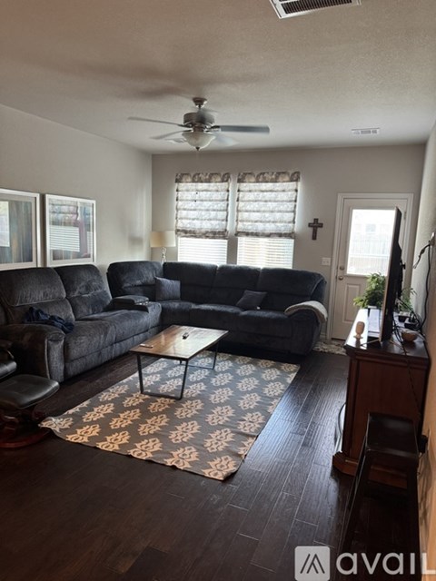 A living room with a black couch and a patterned rug.