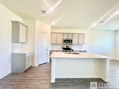 A kitchen with white cabinets and a white island with a sink.