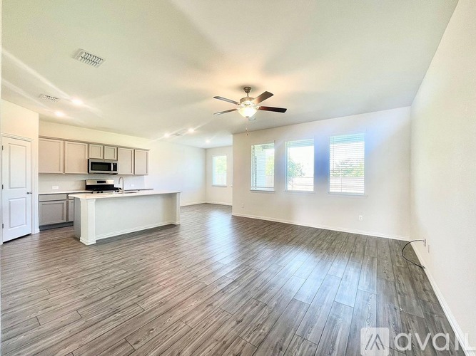 A spacious room with wooden flooring and a ceiling fan.