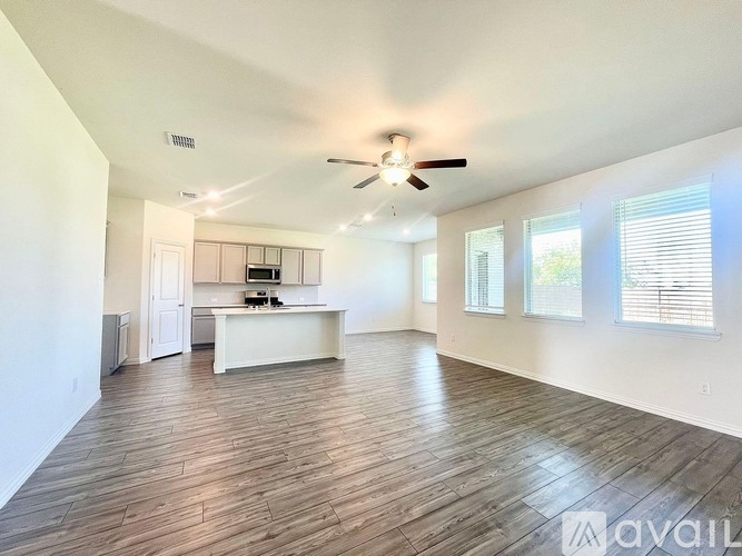 A spacious living room with wood flooring and a ceiling fan.