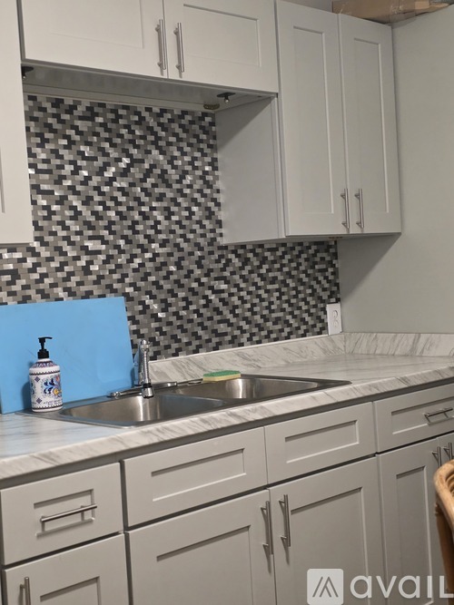 A kitchen with a checkered backsplash and white cabinets.