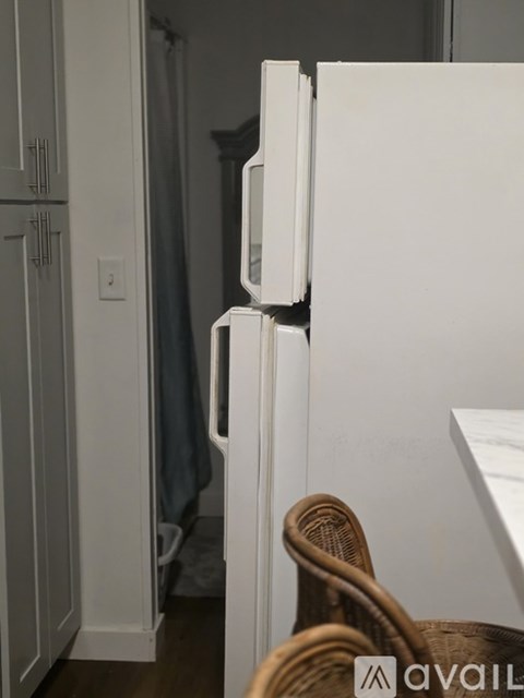A white refrigerator stands in a kitchen next to a cabinet.