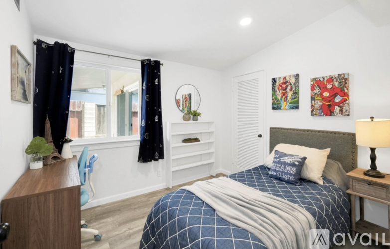 A bedroom with a bed, nightstand, and a window with curtains.