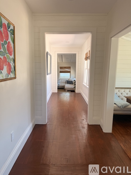 A hallway with a wooden floor and white walls.