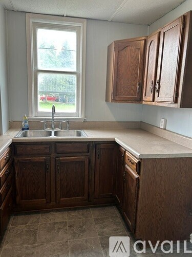 A kitchen with brown cabinets and a window.