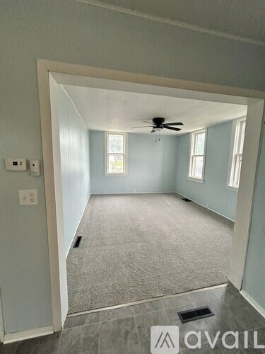 A room with a ceiling fan and carpeted floor.