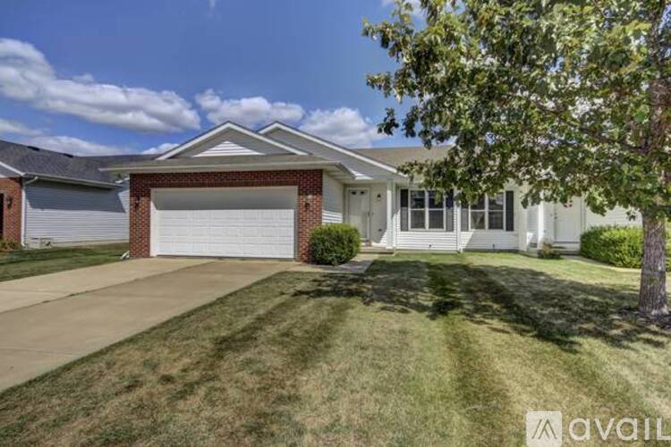 A house with a garage and a tree in front.