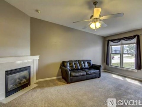 A living room with a black couch and a fireplace.