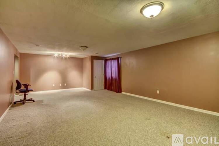 A spacious room with a carpeted floor and a single chair.