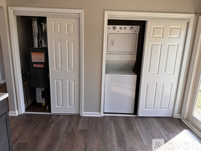 A white door is open to reveal a small kitchen with a dishwasher and oven.