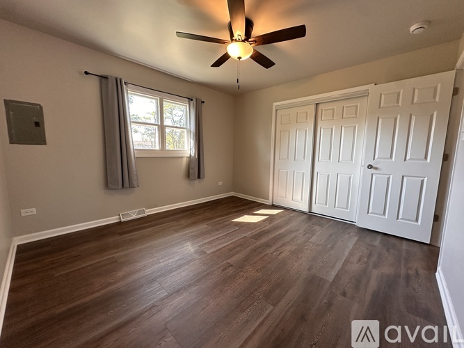 A room with a ceiling fan and wooden flooring.