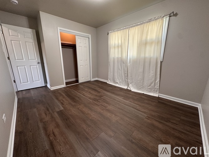 A room with wooden flooring and a doorway leading to another room.