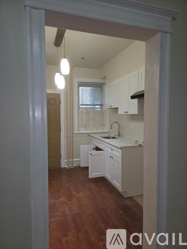 A kitchen with white cabinets and a window.