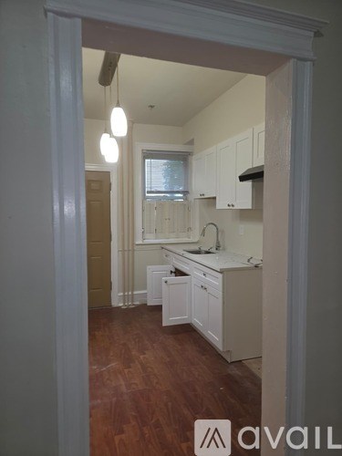 A kitchen with white cabinets and a window.