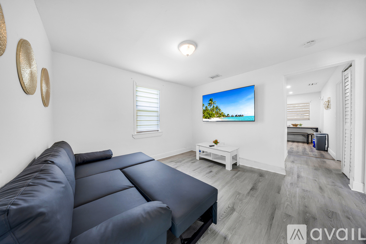 A living room with a large leather sofa and a flat screen TV mounted on the wall.