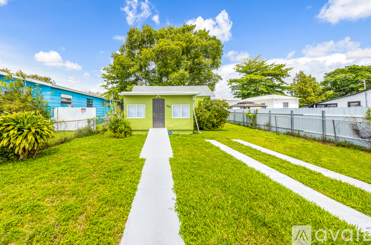 A small green house with a white walkway leading to it.