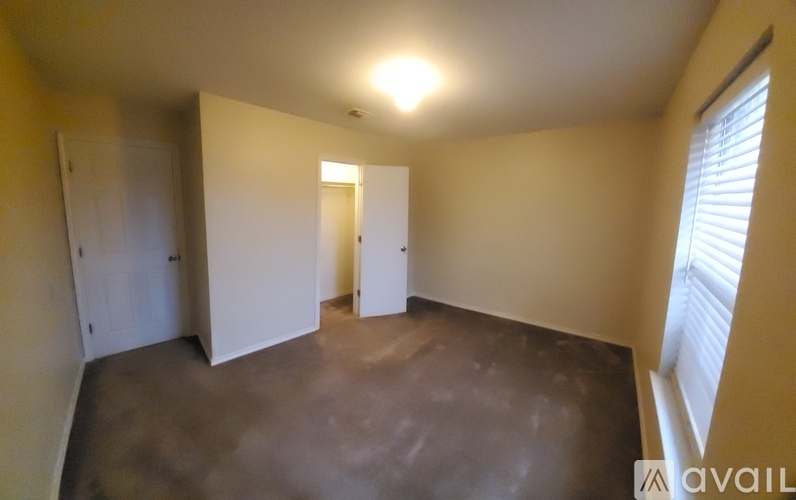 A room with a brown floor and white walls has a window on the right side.