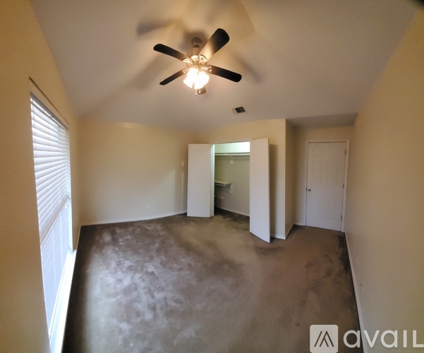 A room with a ceiling fan and a window with blinds.