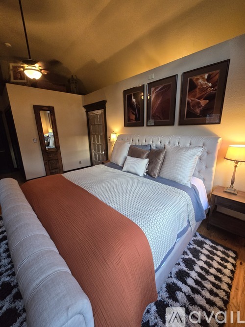 A bedroom with a large bed and two lamps on the side table.