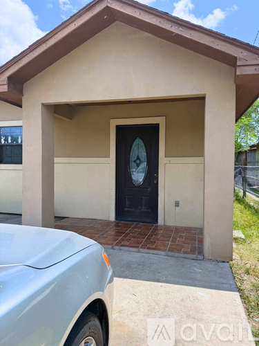 A small house with a black door and a car parked in front.