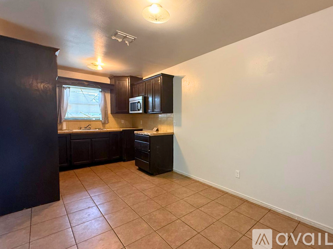 A kitchen with black cabinets and a microwave.