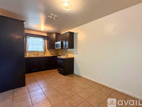 A kitchen with black cabinets and a microwave.