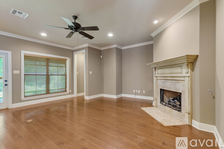 A spacious living room with a fireplace and a ceiling fan.