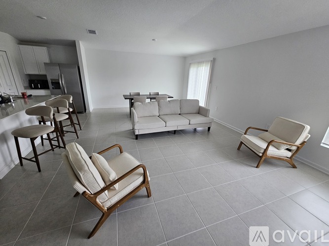 A living room with a white couch and wooden chairs.