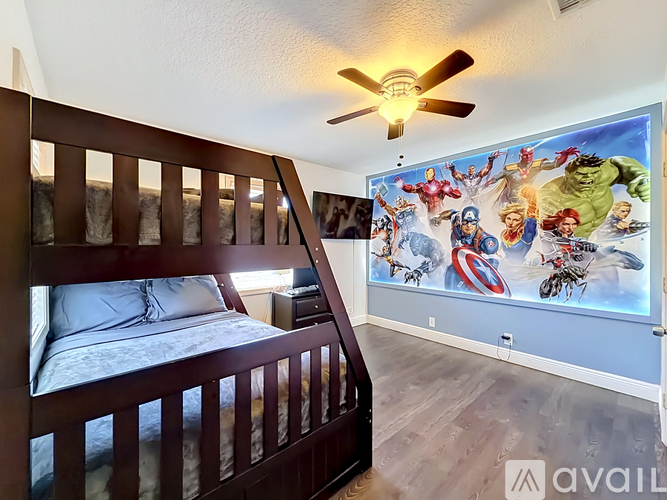 A bedroom with a bed and a wall mural of Marvel superheroes.