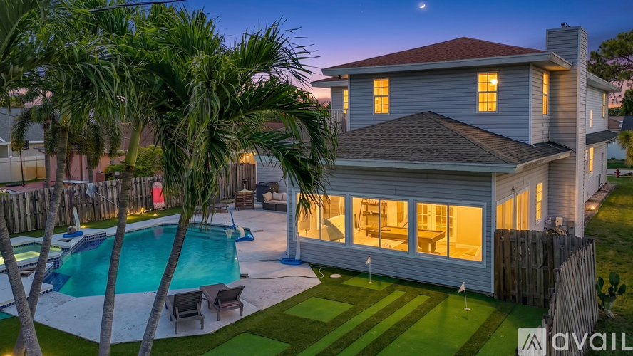 A house with a pool and palm trees in front.