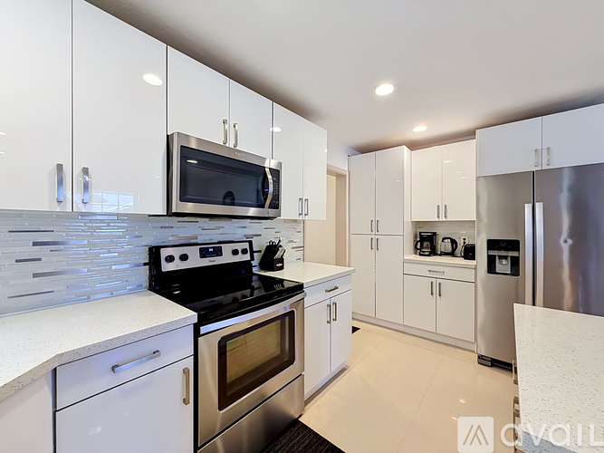 A modern kitchen with white cabinets and stainless steel appliances.