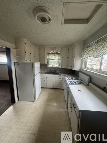 A kitchen with white cabinets and a white fridge.