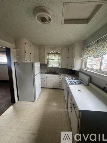 A kitchen with white cabinets and a white fridge.