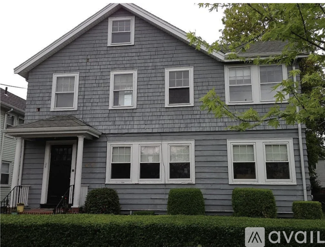 A house with a grey facade and white windows is for sale.