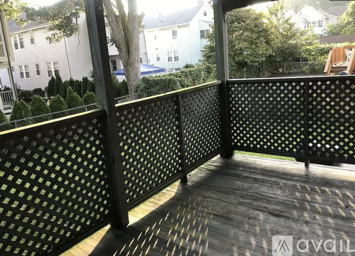 A wooden deck with a lattice fence and a view of a residential area.