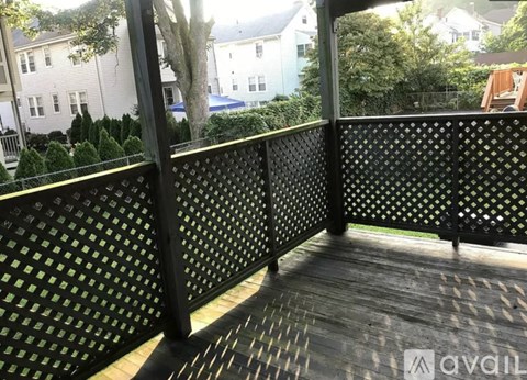 A wooden deck with a lattice fence and a view of a residential area.