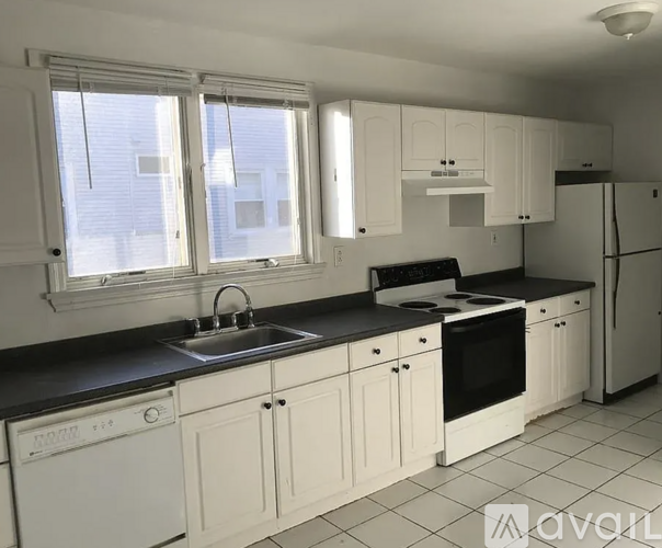 A kitchen with white cabinets and black countertops.