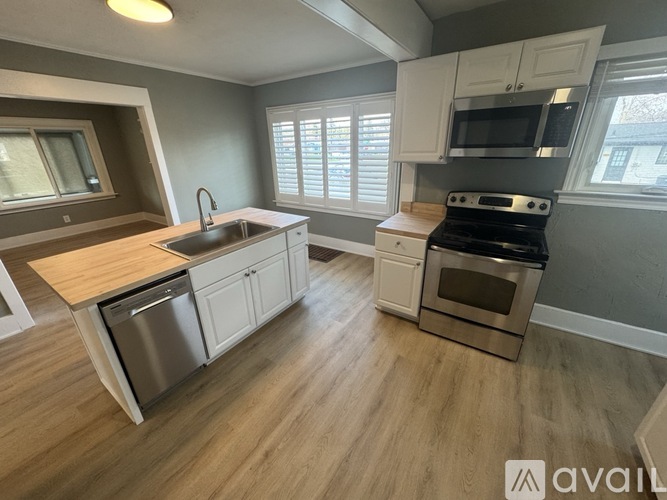 A kitchen with a sink, stove, and cabinets.