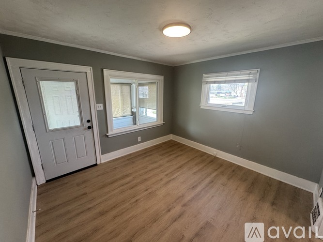A room with a door, a window, and a wooden floor.