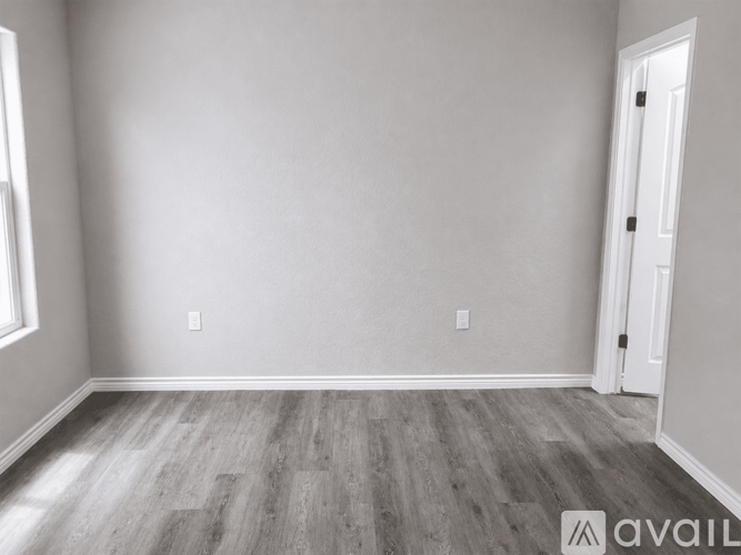 A room with wooden flooring and a white door.
