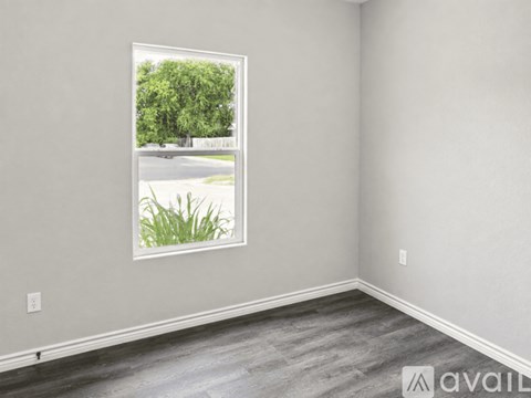 A room with a window showing a street and trees outside.