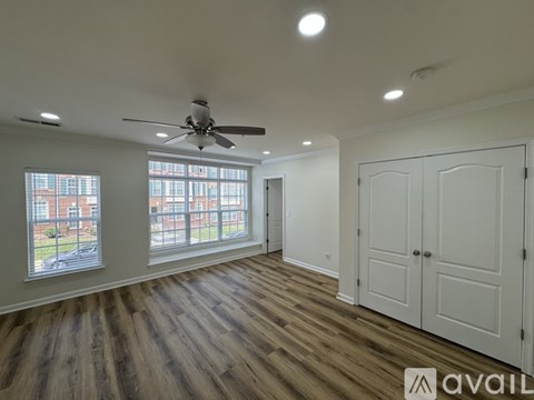 A spacious room with a ceiling fan and large windows.