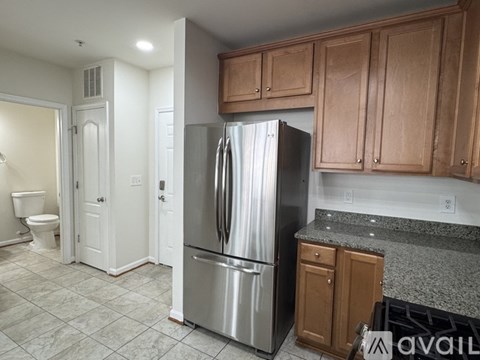 A kitchen with a stainless steel refrigerator and wooden cabinets.