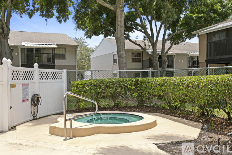 A pool surrounded by a white fence and green bushes.