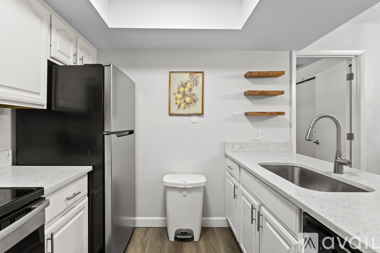 A kitchen with white cabinets and a black refrigerator.