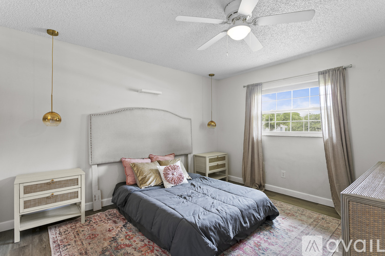 A bedroom with a bed, nightstand, and window.