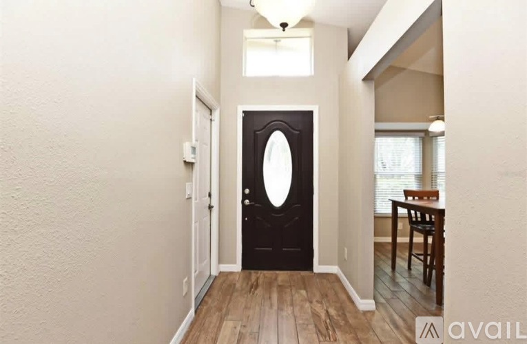 A black door with a round window is in a room with wooden floors.